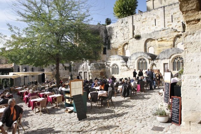 Terrasse en pierres d'un restaurant en pleine été rempli de clients