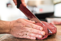 Boucher coupant de la viande à l'aide d'un couteau